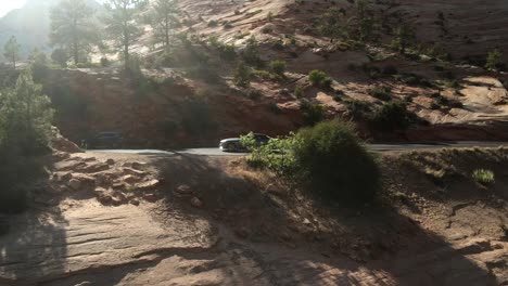 A-cinematic,-aerial-drone-shot-of-Zion-National-Park,-progressing-toward-the-roadway,-and-a-parked-car-on-the-side-of-the-road