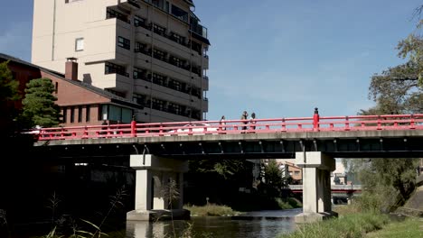 View-Of-Nakabashi-Bridge-Over-Miyagawa-river-in-Takayama-On-Sunny-Afternoon-With-People-And-Traffic-Going-Past
