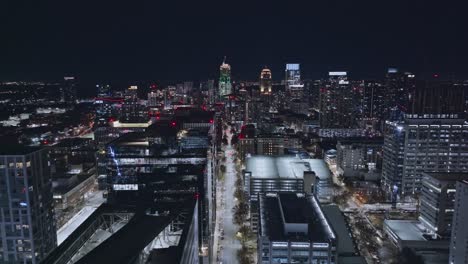 Drone-flight-over-main-road-in-downtown-of-Atlanta-surrounded-by-lighting-skyline-at-night,-Georgia---panorama-view