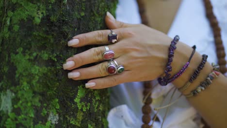 Weibliche-Hand-Mit-Ringen-Und-Armbändern,-Die-Die-Energie-Des-Baumes-Und-Der-Natur-Im-Wald-Streichelt-Und-Sich-Mit-Ihr-Verbindet