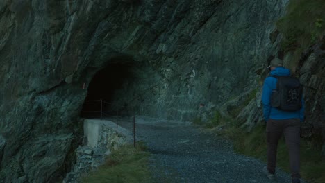 Man-Walking-Towards-Cave-Tunnel-In-Rocky-Mountain-Near-Cima-Fontana,-Valmalenco,-Italy