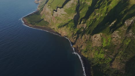 Tilt-up-shot-of-high-cliff-coastline-at-Flores-Azores---drone-shot