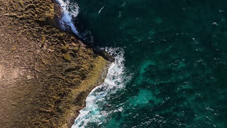Aerial-static-bird's-eye-view-of-volcanic-rock-point-with-crashing-waves
