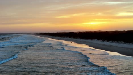 Das-Frühe-Licht-Der-Morgendämmerung-Taucht-Den-Strand-In-Warme-Farbtöne,-Sanfte-Wellen-Streicheln-Das-Ufer