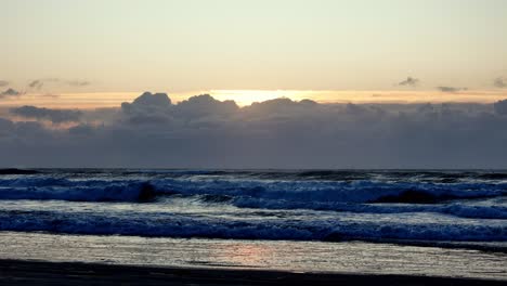The-sun's-radiant-emergence-from-behind-a-blanket-of-morning-clouds,-casting-a-soft-light-upon-the-sea