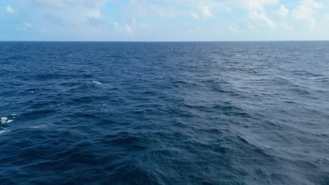 Langsamer-Luftstoß-über-Dem-Beruhigenden-Karibischen-Blauen-Tiefseewasser-Mit-Wolken-Am-Horizont