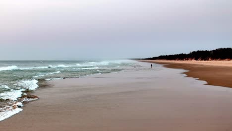 Zwielichtige-Ruhe-An-Einem-Einsamen-Strand:-Sanfte-Wellen-Plätschern-An-Der-Sandigen-Küste,-Wenn-Die-Dämmerung-Hereinbricht