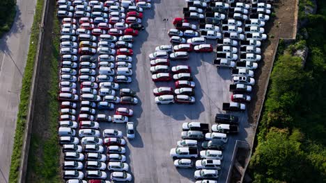 Drone-push-in-tilt-down-over-tightly-parked-cars-awaiting-transport-and-sale