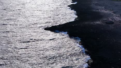Drone-push-in-tilt-down-to-rocky-outcrop-of-basalt-eroded-by-strong-ocean-waves-crashing