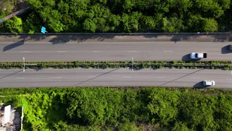 Drone-top-down-static-view-of-compact-cars-driving-along-multi-lane-highway-in-tropical-island