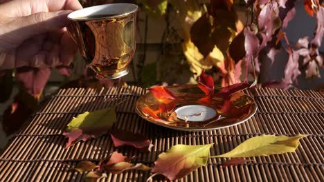 Woman-drinking-coffee-from-golden-coffee-cup-with-colorful-autumn-leaves