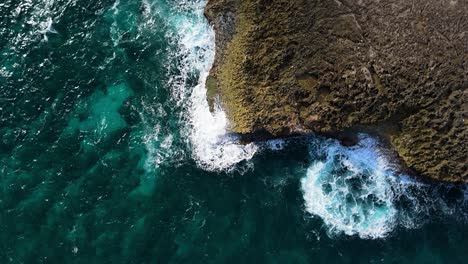 Drone-ascends-and-rotates-as-ocean-waves-batter-jagged-volcanic-coastline-of-island