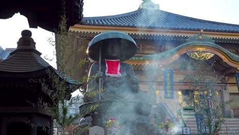 Atemberaubende-Filmische-Aufnahmen-Einer-Statue-Am-Japanischen-Schrein-Mit-Rauch