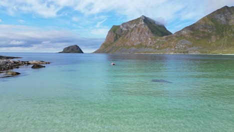 Playa-De-Haukland-Y-Barco-En-El-Mar-ártico-En-Verano-En-La-Isla-De-Lofoten,-Noruega---Antena-4k