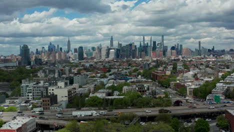 Captivating-drone-push-shot-revealing-Brooklyn's-urban-charm-and-the-iconic-New-York-City-skyline,-with-a-focus-on-the-BQE-in-the-foreground