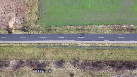 Patchy-country-road-ascending-drone-top,-down