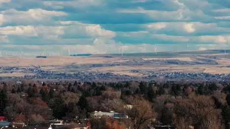 Drone-shot-of-many-windmills-turning-in-the-distance-outside-of-Idaho-Falls,-ID