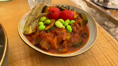 Tasty-French-ratatouille-dish-with-stewed-vegetables,-cherry-tomatoes-and-Japanese-edamame-beans-in-a-bowl,-4K-shot