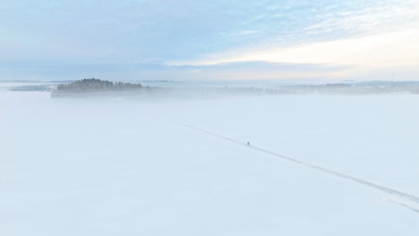 A-couple,-two-people,-walking-on-a-road-or-path-on-ice-towards-a-small-cape-on-a-frozen-lake-in-Tammela,-Finland