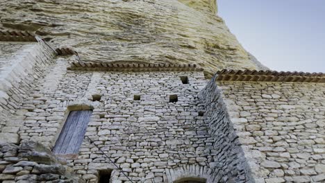 Altes-Steinhaus-Aus-Rauen-Steinen-Auf-Einem-Hohen-Felsen-In-Der-Sonne-Mit-Alten-Holzfenstern,-Verlassen-In-Frankreich