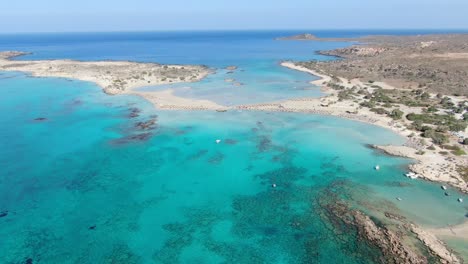 Drohnenansicht-In-Griechenland,-Die-An-Einem-Sonnigen-Tag-über-Den-Schmalen-Weißen-Sandstrand-Von-Elafonisi,-Klares-Blaues-Wasser-An-Den-Seiten-Und-Braune-Landschaft-Fliegt