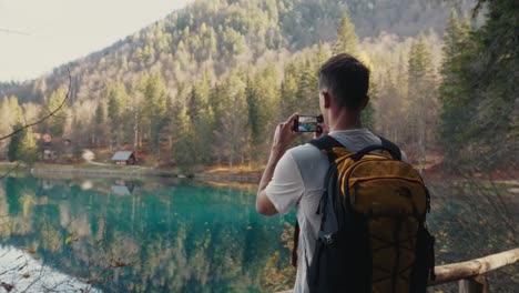 Man-taking-photos-near-a-mountain-lake-with-turquoise-color