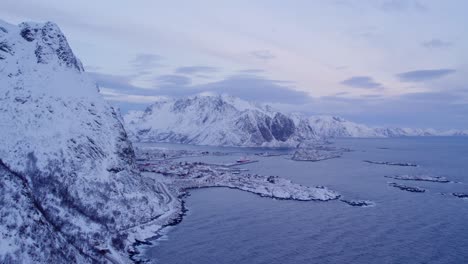 Breathtaking-view-of-Lofoten-with-snow-covered-mountains,-a-serene-body-of-water,-and-a-small-settlement-nestled-between-the-natural-elements