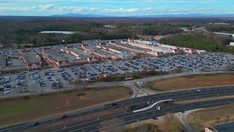 Aerial-lateral-shot-if-traffic-on-highway-and-busy-parking-lot-at-american-Shopping-mall-during-Christmas-time