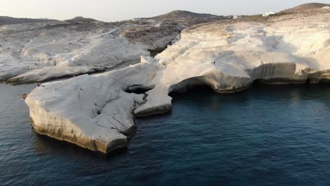 Vista-De-Drones-En-Grecia-Volando-Sobre-Una-Zona-De-Roca-Blanca-En-Forma-De-Luna-En-La-Isla-De-Milos-Al-Amanecer-Junto-Al-Mar-Azul-Oscuro