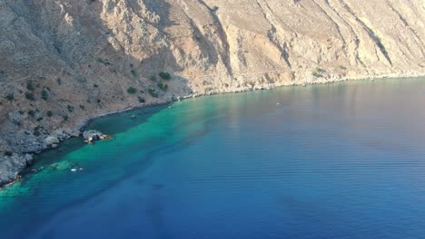 Vista-De-Drones-En-Grecia-Dando-Vueltas-Alrededor-De-Una-Colina-Marrón-En-Una-Montaña-Junto-Al-Mar-Azul-Del-Mediterráneo-En-Un-Día-Soleado