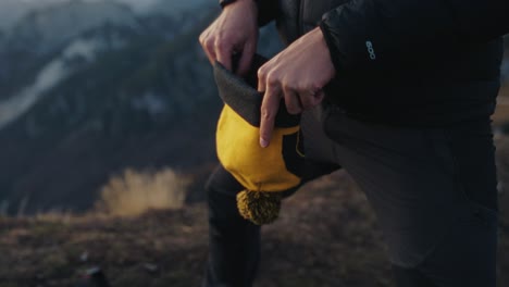 Man-putting-on-his-beanie-during-a-hike-in-the-mountains