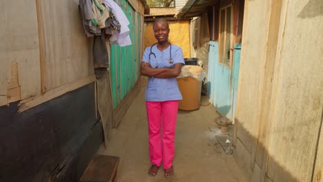 Mujer-Africana-Enfermera-Negra-Doctora-Cruzando-Los-Brazos-Frente-A-La-Cámara-Sonriendo-Y-Usando-Una-Bata-De-Laboratorio-Azul-Y-Un-Estetoscopio,-Concepto-De-Atención-Médica-En-África
