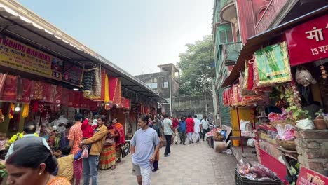 Menschen,-Die-In-Der-Nähe-Des-Weges-Zum-Kalighat-Tempel-Mit-Mehreren-Geschäften-Gehen,-Die-Religiöse-Materialien-Verkaufen