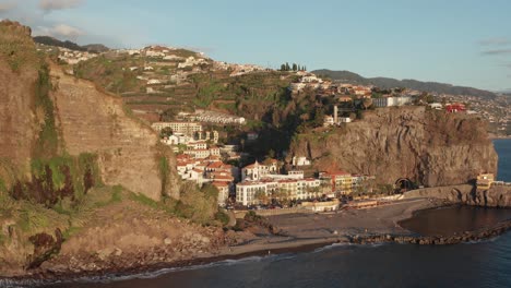Tranquila-Y-Serena-Ciudad-Costera-Junto-Al-Océano-Lentamente-Revelada-Detrás-De-La-Montaña-Durante-La-Puesta-De-Sol-En-Ponta-Do-Sol,-Madeira,-Portugal
