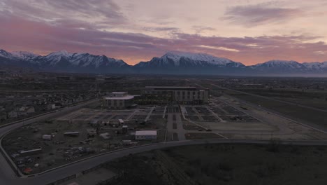 Lehi,-Utah-at-dawn-in-winter-below-snow-capped-mountains---aerial