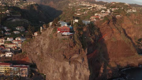 Scenic-coastal-city-with-buildings-on-top-of-a-mountain-range-and-in-valley-during-sunset-in-Ponta-Do-Sol,-Madeira,-Portugal