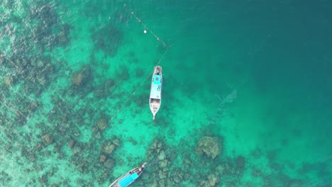 Long-tail-tour-boats-at-reef-in-emerald-clear-water,-Aerial-reveal