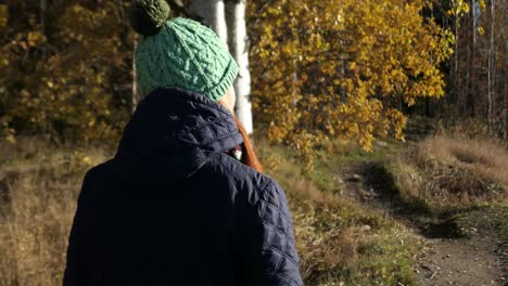 Woman-walking-into-forest-in-sunny-autumn-day