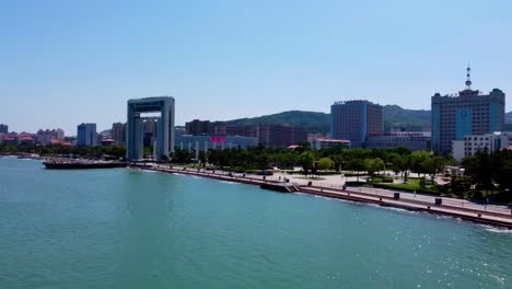 Aerial-dolly-view-Xingfu-park-flying-from-sea-side-flying-toward-the-city---Weihai-China