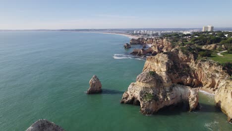 Portimao-rugged-cliff-coast-with-emerald-ocean-sea-water,-aerial-view,-Portugal