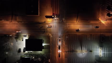 Intersection-with-traffic-moving-in-Little-Rock,-Arkansas-downtown-at-night-with-drone-video-stable