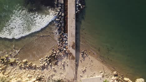 Top-down-aerial-shot-of-pier-wave-breaker-in-Ferragudo,-Portugal,-aerial