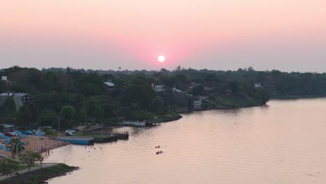 Aerial-footage-of-two-kayaks-sailing-along-the-coast-at-sunset-in-Misiones,-Posadas,-Argentina