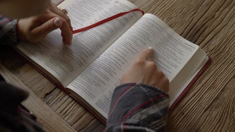 Blick-Auf-Weibliche-Hände,-Die-Am-Heimischen-Schreibtisch-Bibeltexte-Lesen-Und-Studieren