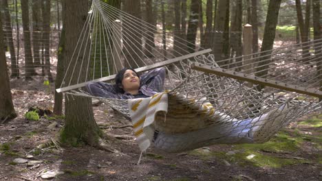 Comfortable-Puerto-Rican-female-swinging-in-forest-hammock-peaceful-daydreaming