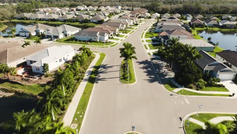 Aerial-view-entering-a-sunny-suburban-neighborhood-in-tropical-climate