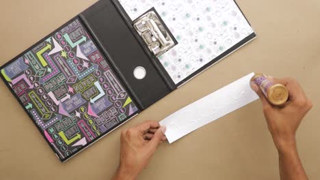 Applying-glue-on-piece-of-paper-to-place-in-scrapbook-with-cool-design
