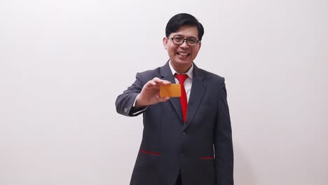 Happy-asian-businessman-standing-while-showing-a-blank-card