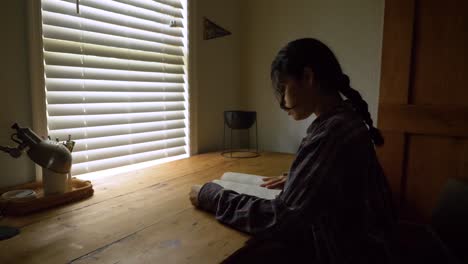 Puerto-ricanische-Studentin,-Die-Am-Schreibtischfenster-Des-Schlafzimmers-Sitzt-Und-Ein-Lehrbuch-Liest