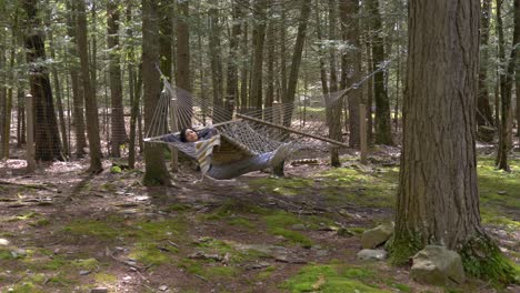 Carefree-young-female-swinging-in-woodland-forest-hammock-relaxed-and-peaceful